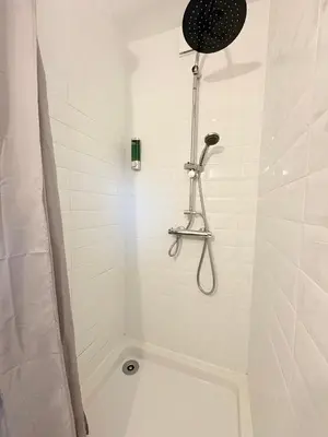 a white bathroom with a shower with a shower head at Le Faubourg in Pamiers