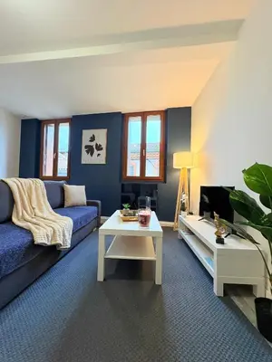 a living room with a blue couch and a tv at Le Faubourg in Pamiers