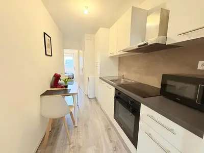 a kitchen with white cabinets and a sink and a microwave at Le Faubourg in Pamiers