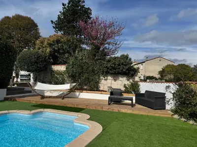 a backyard with a hammock and a swimming pool at Maison 3 chambres, piscine privée terrain de pétanque in Carcassonne