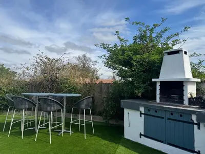 a backyard with a grill and a table and chairs at Maison 3 chambres, piscine privée terrain de pétanque in Carcassonne