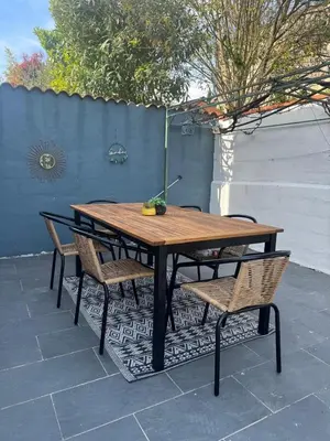 a wooden table with two chairs and a table with a plant on it at Maison 3 chambres, piscine privée terrain de pétanque in Carcassonne