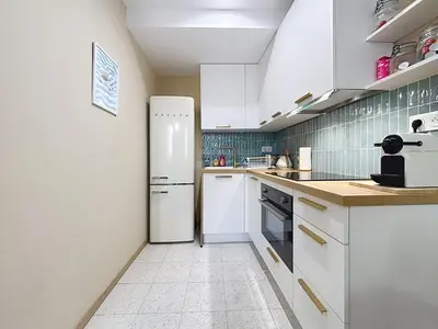 a kitchen with a refrigerator and a tile floor at Le Saint Just - Appartement face à la Cathédrale in Narbonne
