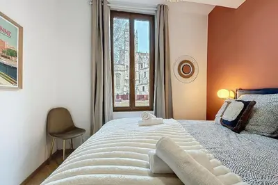 a bedroom with a large bed and a window at Le Saint Just - Appartement face à la Cathédrale in Narbonne