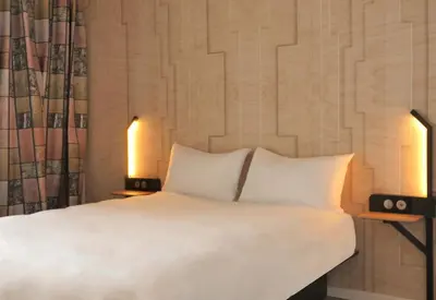 a bedroom with a bed with two lamps and two pillows at B&B HOTEL Carcassonne Rocadest La Cité in Carcassonne