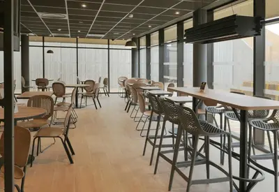 a restaurant with tables and chairs and windows at B&B HOTEL Carcassonne Rocadest La Cité in Carcassonne
