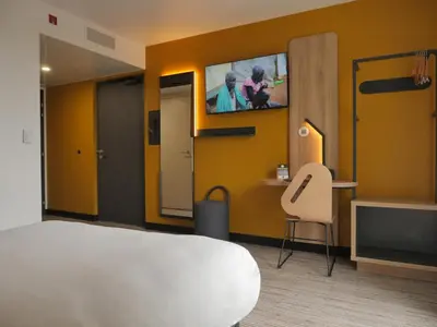 a room with a bed and a tv on a wall at B&B HOTEL Carcassonne Rocadest La Cité in Carcassonne