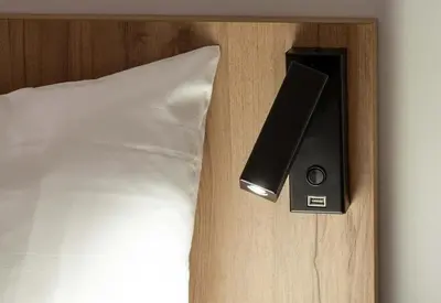 a bed with a speaker next to a white pillow at B&B HOTEL Carcassonne Rocadest La Cité in Carcassonne