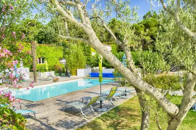 a swimming pool in a yard with chairs and a tree at le Relais de la Cavayere in Carcassonne