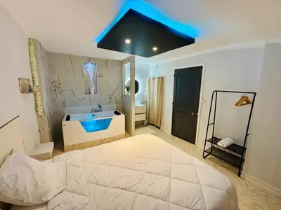 a large bathroom with a large bed and a tub at Sereni house jacuzzi in Narbonne