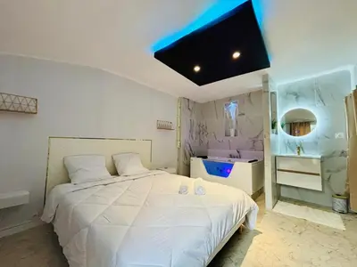 a bedroom with a white bed and a flat screen tv at Sereni house jacuzzi in Narbonne