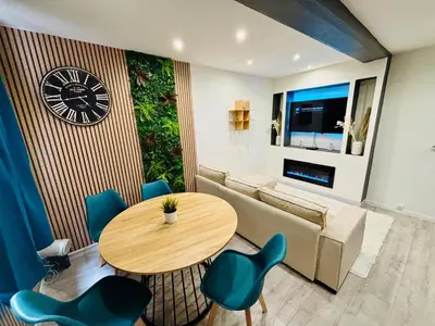 a living room with a table and a couch and a clock at Sereni house jacuzzi in Narbonne