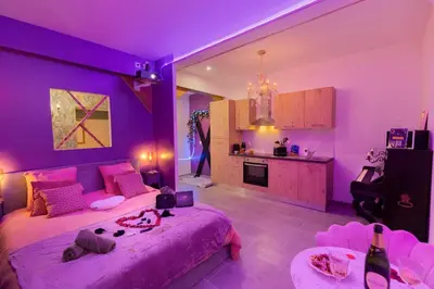 a purple bedroom with a large bed and a kitchen at Le bridgerlove Tantra Jacuzzi Unique in Quillan