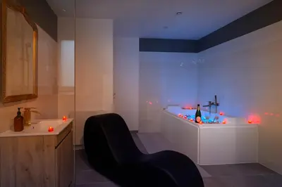 a bathroom with a black chair and a sink at Le bridgerlove Tantra Jacuzzi Unique in Quillan