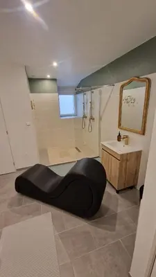 a bathroom with a large black ottoman in front of a shower at Le bridgerlove Tantra Jacuzzi Unique in Quillan