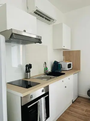 a kitchen with white cabinets and a sink and a microwave at L'atypique l 2 chambres l Clim in Castres