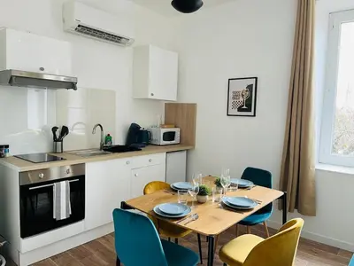 a kitchen with a wooden table with chairs and a dining room at L'atypique l 2 chambres l Clim in Castres