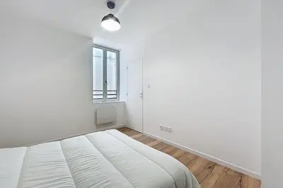 a white bedroom with a bed and a window at Bright 1-bedroom apartment in Cuxac-dʼAude