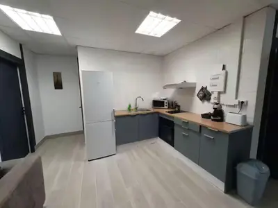 a kitchen with gray cabinets and a white wall at la tanière argentée in Nailloux