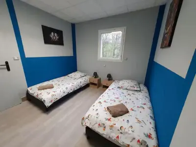 a bedroom with two beds and a window at la tanière argentée in Nailloux