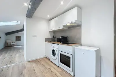 a kitchen with white cabinets and a washer and dryer at Spacious studio for two in Cuxac-d'Aude in Cuxac-dʼAude