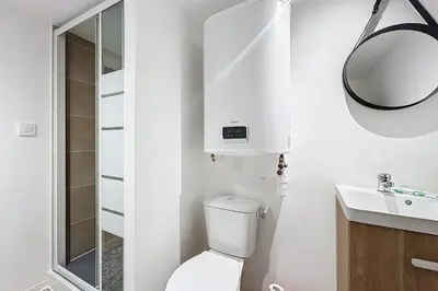 a white bathroom with a toilet and a mirror at Spacious studio for two in Cuxac-d'Aude in Cuxac-dʼAude