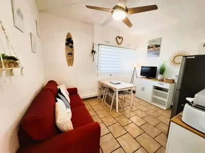 a living room with a red couch and a table at Rez de jardin climatisé avec grande terrasse in Gruissan