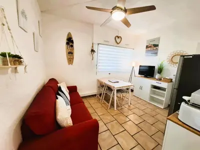 a living room with a red couch and a table at Rez de jardin climatisé avec grande terrasse in Gruissan
