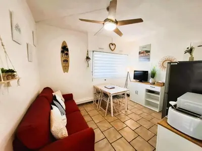 a living room with a red couch and a table at Rez de jardin climatisé avec grande terrasse in Gruissan