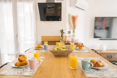 a table with plates of food and cups of orange juice at Magnifique T3-terrasse-parking-Centre ville-AD in Carcassonne