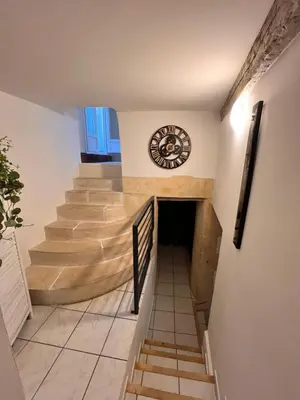 a staircase in a building with a clock on the wall at Charmante Maison de Village avec Terrasse in Olonzac