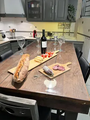 a wooden table with a bottle of wine and wine glasses at Charmante Maison de Village avec Terrasse in Olonzac