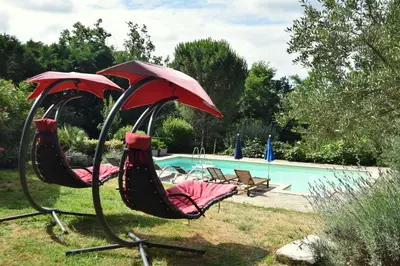 two chairs with umbrellas sitting next to a pool at Aux portes du Sidobre in Burlats