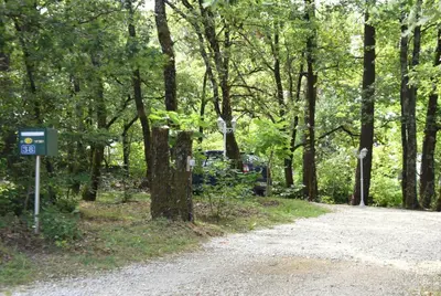a dirt road with a sign in the woods at Aux portes du Sidobre in Burlats