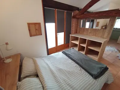 a bedroom with a bed in a room with windows at La maison au bout de l'allée in Carbes