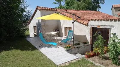 a patio with a table and chairs and an umbrella at La maison au bout de l'allée in Carbes