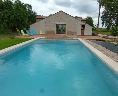 a large blue swimming pool in front of a house at La maison au bout de l'allée in Carbes