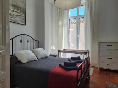 a bedroom with a bed with a red blanket and a window at Le charme à la française - Appartement 4 pers in La Redorte