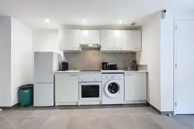 a kitchen with white cabinets and a washer and dryer at Bright T3 for 4 people in Cuxac-dʼAude