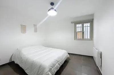 a white bedroom with a bed and a window at Bright T3 for 4 people in Cuxac-dʼAude