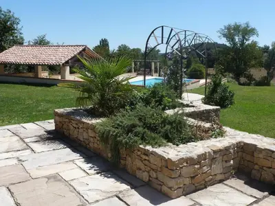 a garden with a stone wall next to a swimming pool at Charming cottage style property nestled in stunning French countryside near Carcassonne and Mirepoix in Hounoux
