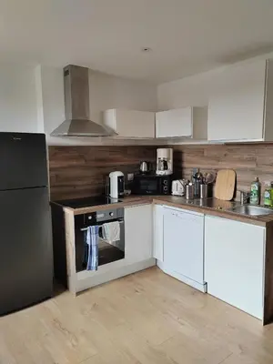 a kitchen with white cabinets and a black refrigerator at Beau T3 coeur village in Gruissan