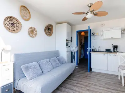 a living room with a couch and a kitchen at Studio cabine avec terrasse, animaux admis, pour 4 personnes - FR-1-409A-33 in Gruissan