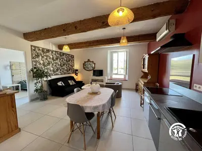 a kitchen and a living room with a table in a room at L'abeille in Durban-Corbières