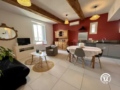 a living room with a table and a kitchen at L'abeille in Durban-Corbières