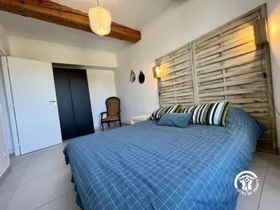 a bedroom with a blue bed with a wooden headboard at L'abeille in Durban-Corbières