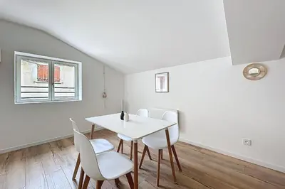 a white dining room with a table and chairs at T3 apartment in the heart of Cuxac-d'Aude in Cuxac-dʼAude