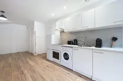 a kitchen with white cabinets and a washing machine at T3 apartment in the heart of Cuxac-d'Aude in Cuxac-dʼAude