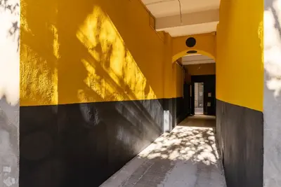 an empty hallway with a yellow wall and a sidewalk at La PARERIE 2 in Carcassonne