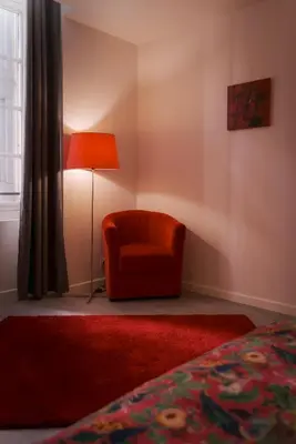 a bedroom with a red chair and a lamp at La PARERIE 2 in Carcassonne